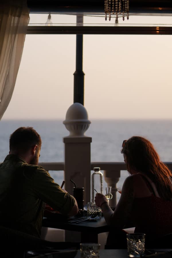 A couple dining as the sun sets over the Atlantic