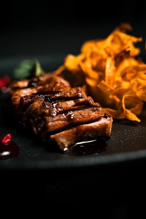 Close-up of sliced meat with glaze and a crisp garnish