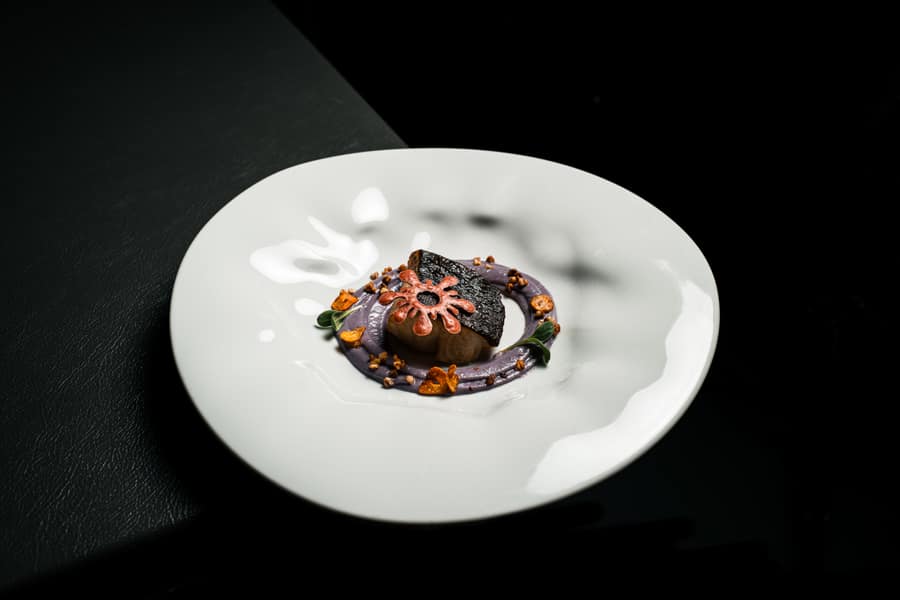 Seafood dish served on a white plate against a dark background