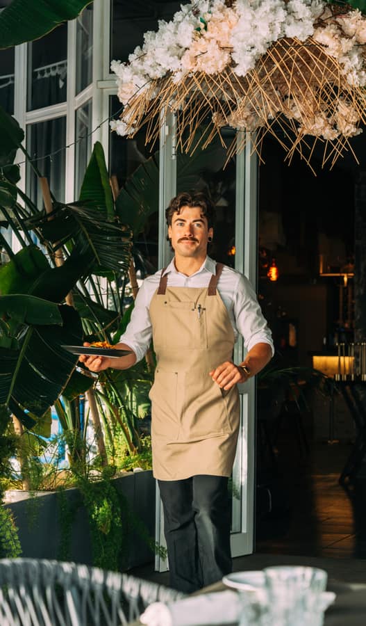 Waiter welcoming guests at the dining room entrance