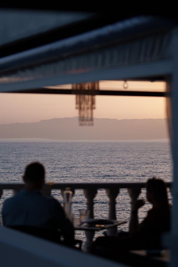 Two diners silhouetted against the sea at sunset